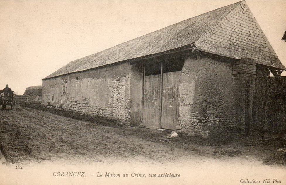 Photo en noir et blanc d'une vieille ferme en pierre avec un toit en pente et de grandes portes de grange, stylisée comme une mise en page Elementor. Une calèche roule à gauche sur le chemin de terre. Légende : CORANCEZ - La Maison du Crime, vue extérieure.